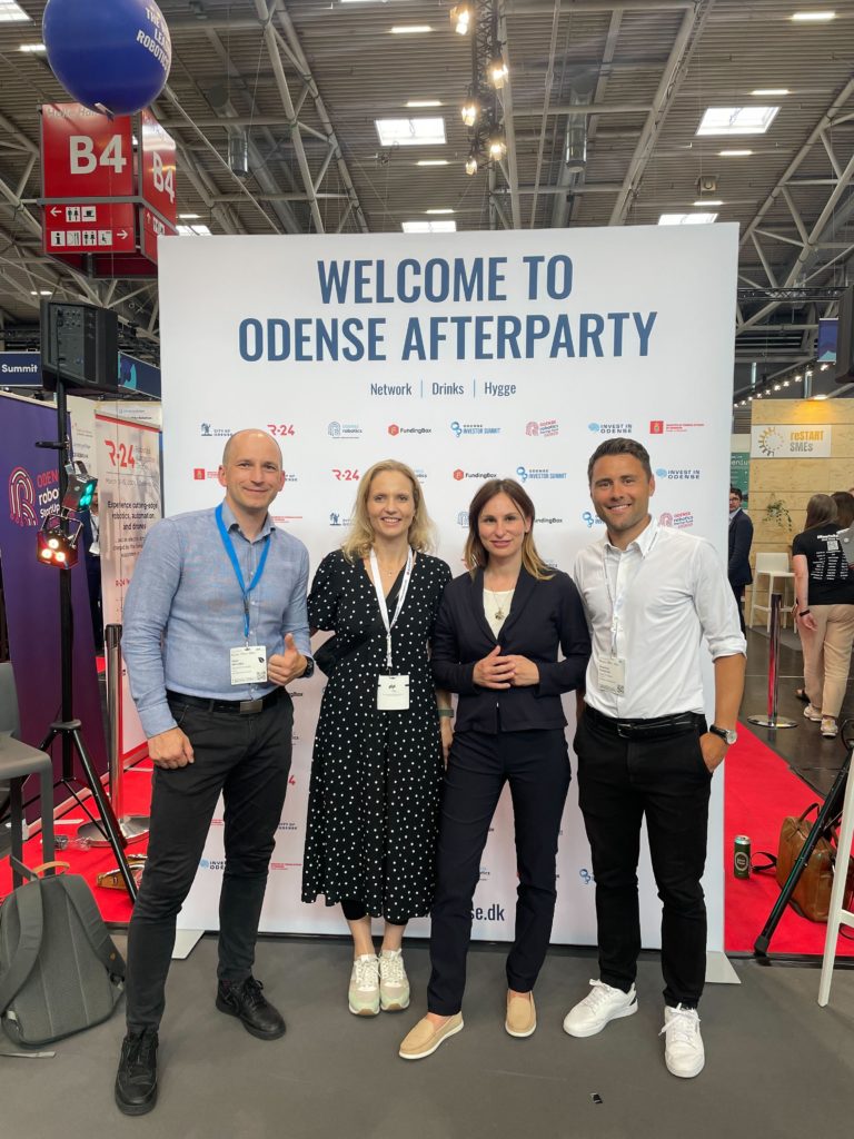 Two women and two men standing in front of a promotional wall that says "WELCOME TO ODENSE AFTERPARTY"